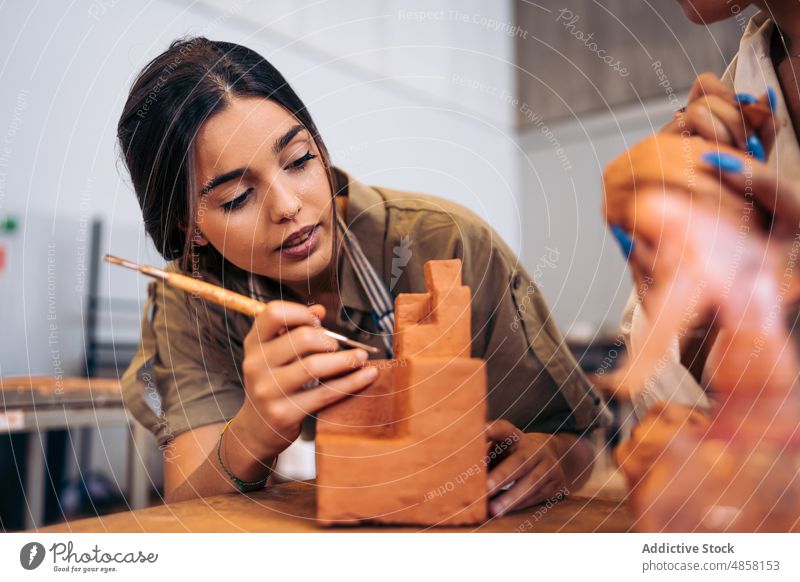 Junge Handwerkerin schnitzt geometrische Formen aus Ton schnitzen Geometrie Atelier Porträt kreativ handgefertigt Frau jung hispanisch ethnisch Tisch