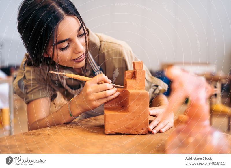 Junge Handwerkerin schnitzt geometrische Formen aus Ton schnitzen Geometrie Atelier Porträt Lächeln kreativ handgefertigt Frau jung hispanisch ethnisch Tisch