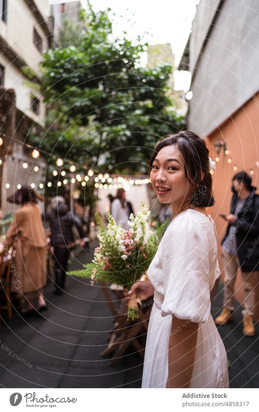 Junge ethnische Braut mit Blumenstrauß Frau Hochzeit Lächeln feiern Heirat Straße Verlobte asiatisch Chinesisch Blütezeit Zahnfarbenes Lächeln Glück heiter