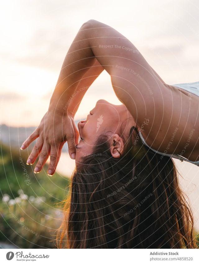 Friedliche Frau, die eine Rückbeuge mit Namaste-Geste während einer Yoga-Sitzung in der Natur macht Backend Augen geschlossen Wohlbefinden Asana Sonnenuntergang