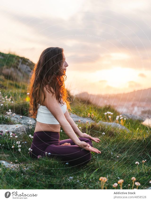 Junge Frau sitzt in Lotus-Pose und meditiert in der Natur meditieren Athlet Sportkleidung Hügel padmasana üben Yoga Asana Mudra Sportbekleidung grasbewachsen