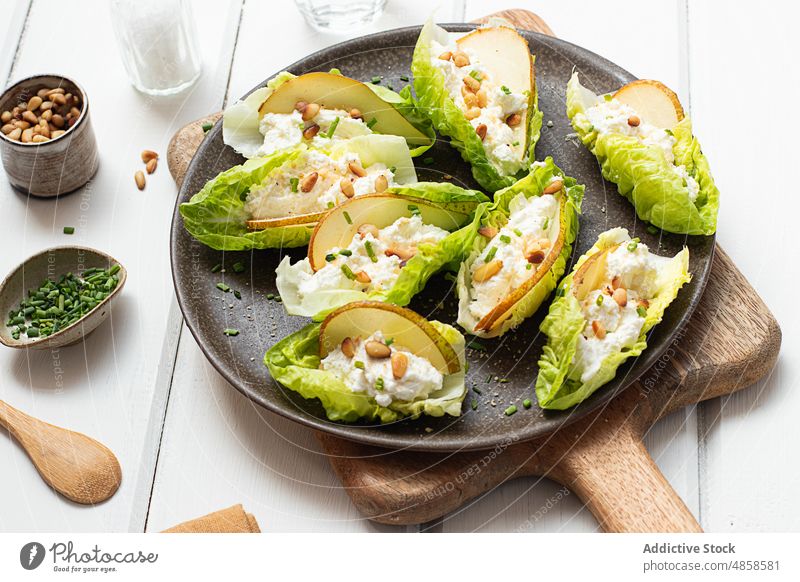 Birnen-Ricotta-Salat mit Kopfsalat auf Holztisch Hintergrund geschmackvoll natürlich Scheiben Gemüse Ritzel Samen Käse Mahlzeit Abendessen Bestandteil grün