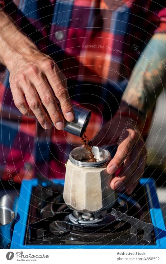 Crop Man gibt gemahlenen Kaffee in die Kaffeemaschine Mann hinzufügen Moka-Topf vorbereiten Boden frisch Morgen Campingplatz Herd männlich früh brauen Koffein