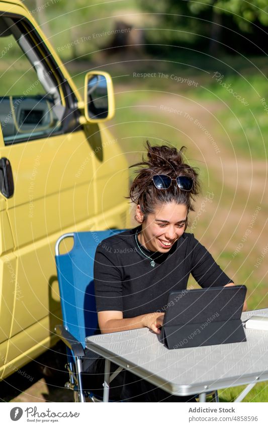 Hispanische Frau benutzt Tablet außerhalb des Wohnmobils Tablette benutzend Landschaft Kleintransporter Lächeln Daten freiberuflich Wochenende Sommer hispanisch