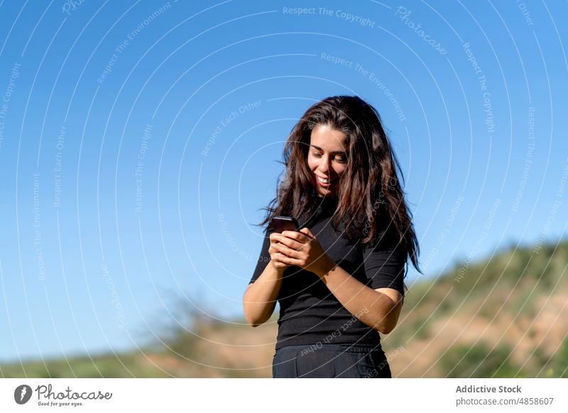Hispanische Frau benutzt Smartphone auf dem Land benutzend Lächeln Landschaft Wochenende Texten Sommer online Tourist brünett hispanisch ethnisch Natur tagsüber