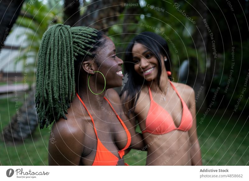 Fröhliche schwarze Frauen in Badeanzügen stehen in der Nähe des Haines Freund Bonden Bikini tropisch Freizeit Zeitvertreib Zeit verbringen Hinterhof