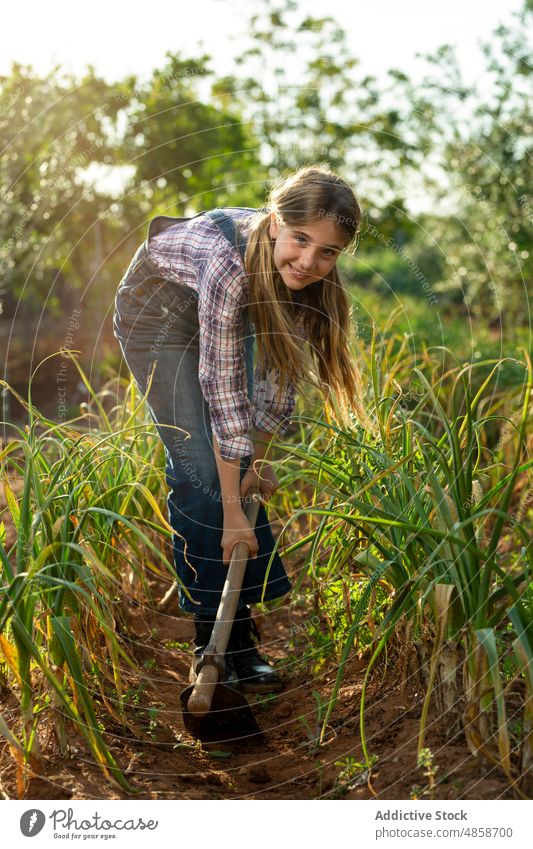 Mädchen hackt Erde in der Nähe von Frühlingszwiebeln Hacke Feld Gärtner Bauernhof Unkraut entfernen Sommer Ackerbau Landschaft ländlich kultivieren tagsüber