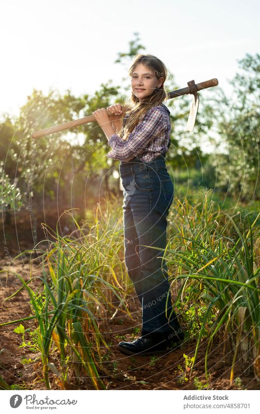 Positiver kleiner Bauer mit Hacke Mädchen Landwirt Sommer Landschaft Ackerbau Bauernhof Arbeit Frühlingszwiebel Porträt führen lässig ländlich Kind Sonnenlicht