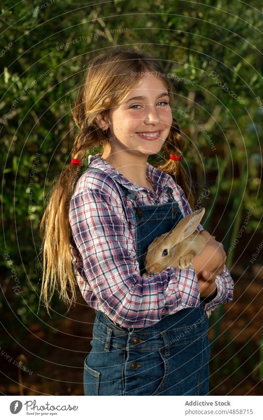 Kleiner Bauer mit Kaninchen im Garten Mädchen Landwirt Landschaft Umarmung Lächeln Sommer Bauernhof Tier Porträt positiv tagsüber Kind lässig heiter Glück Hase