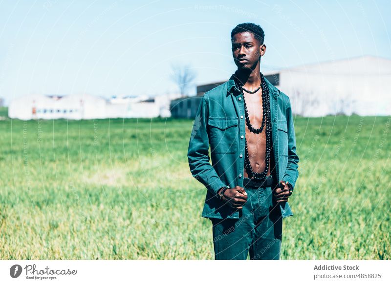 Afrikanischer Mann in Jeanskleidung auf dem Land Stil Landschaft Mode Outfit Jeansstoff Tradition Sommer Gras Model lässig Accessoire ethnisch schwarz