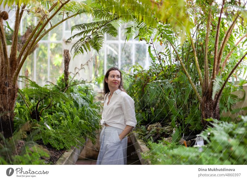Junge Frau im Gewächshaus mit tropischen Pflanzen auf Reisen und bewundert die Schönheit der Natur. Weiblicher Tourist besucht botanischen Garten, studiert Pflanzen.