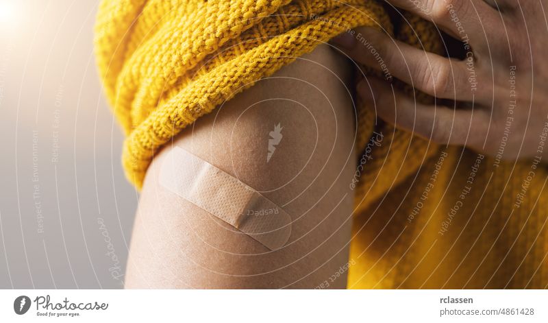 Impfstoff gegen Corona COVID-19 und SARS cov. Frau, die den Ärmel ihres Pullovers hochhält und ihren Arm mit einem Pflasterverband zeigt, nachdem sie eine Impfung erhalten hat, Bannergröße
