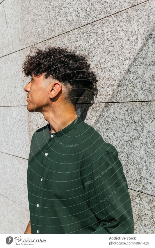 Junger stilvoller Mann auf der Straße Stil Model trendy anlehnen Steinwand Starrer Blick Großstadt Streetstyle modern männlich ethnisch Afro-Look krause Haare