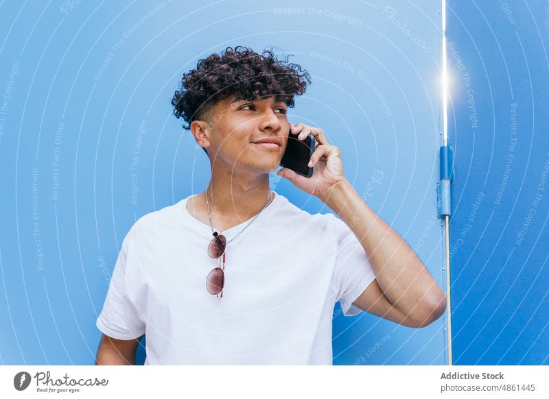 Junger ethnischer Mann beim Telefonieren auf der Straße Smartphone sprechend Mobile Lifestyle positiv online Internet soziale Netzwerke Gerät modern männlich