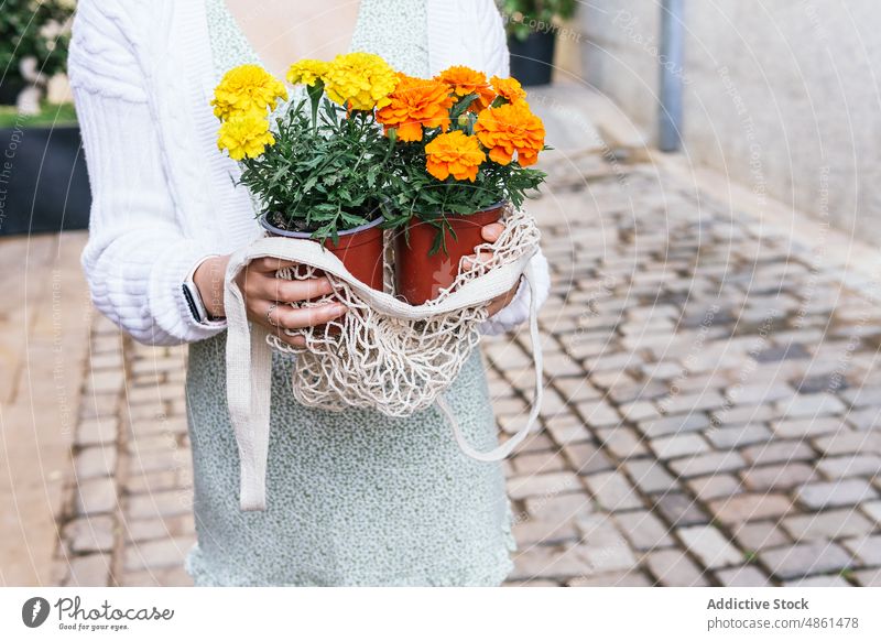 Frau mit Blumen in Töpfen auf der Straße Ringelblume Laden geblümt Blumentopf Pflanze Vitrine Großstadt beobachten Interesse Fenster Kunde eingetopft Wahl