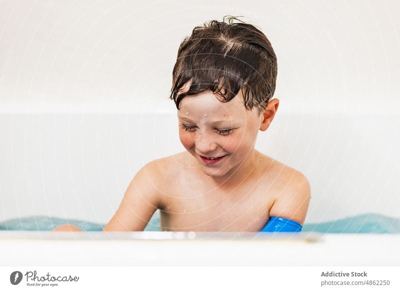 Junge mit wasserfestem Armgips in der Badewanne wasserdicht verputzen Lachen Kind Spaß haben weiß modern spielen sorgenfrei zu Hause Lächeln