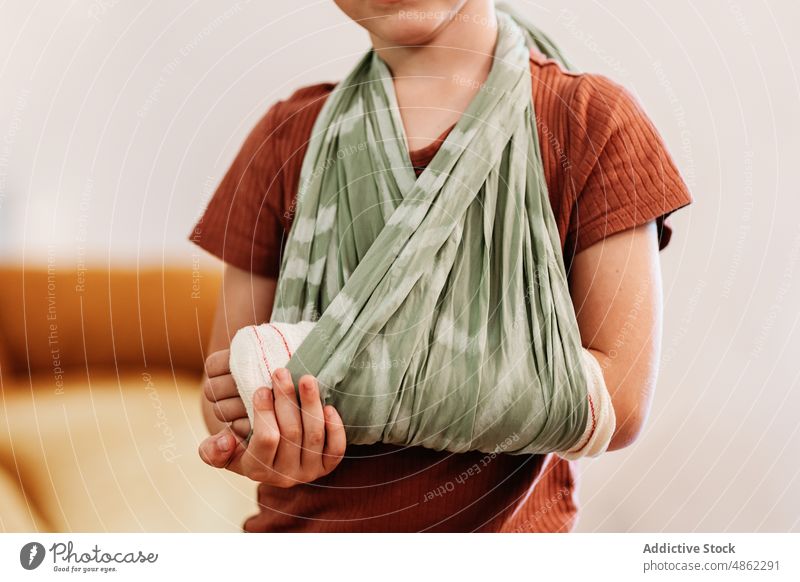 Ein Kind mit gebrochenem Arm in einer Schlinge Arme bandagieren Babytragetuch verputzen Verletzung Unfall heimwärts vorbereiten Stoff geduldig Wunde Kindheit