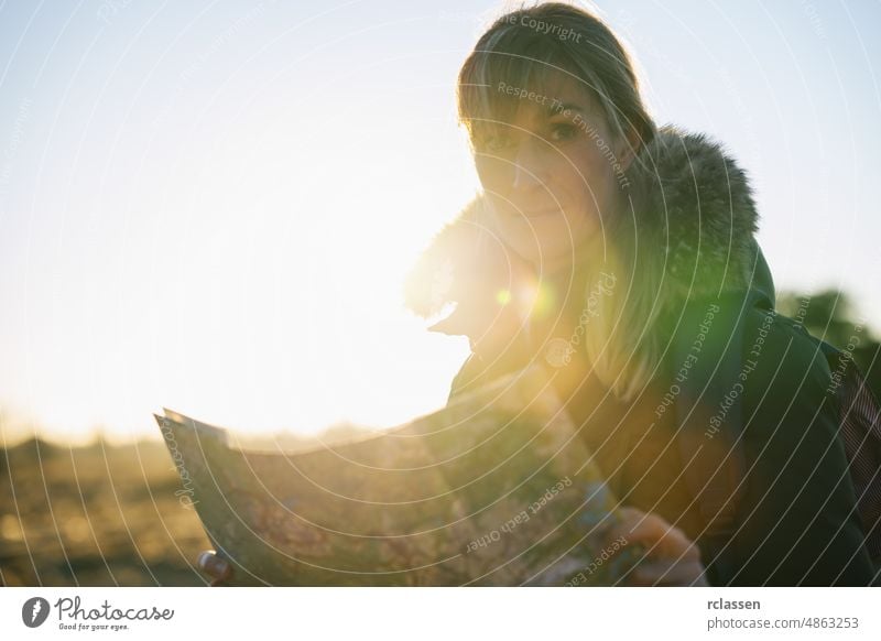 Frau Wanderer mit einem Rucksack und eine Karte, die Suche nach der richtigen Richtung in der Wildnis bei Sonnenuntergang Landkarte Trekking wild schön Regie