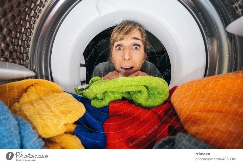 Hausfrau Reaching Inside einer Waschmaschine oder Trockner zu Hause Blick von Waschmaschine innen stürzen im Inneren Wäscherei Maschine erreichend Vorrichtung