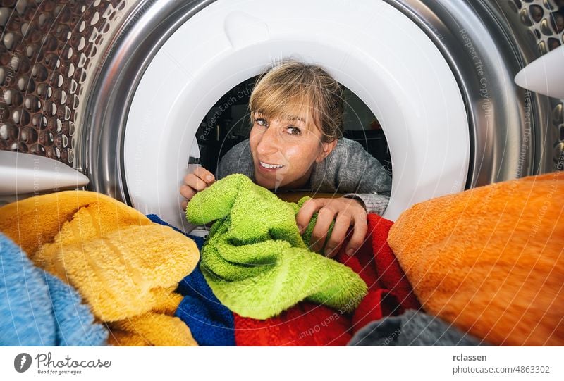 Frau, die in eine Waschmaschine oder einen Trockner in einer Wäscherei greift stürzen im Inneren Maschine erreichend Vorrichtung Kaukasier Arbeit Kleidung