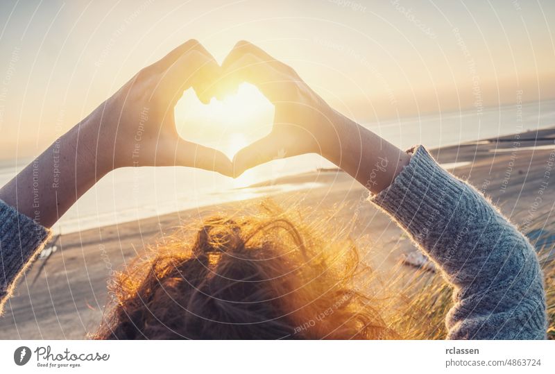 Frau Hände in Herz-Symbol geformt mit Sonnenuntergang Licht am Strand, Lifestyle und Gefühle Konzeptbild Hand reisen Liebe Harmonie Kräusel Sonnenlicht