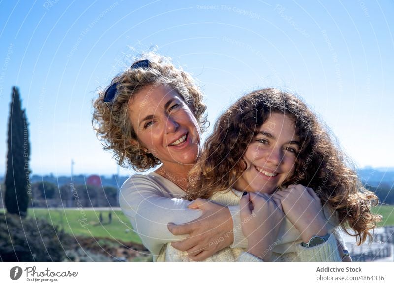 Lächelnde Mutter umarmt Tochter an einem sonnigen Tag umarmend Himmel Liebe Glück Bonden Familie Zusammensein Genuss Lifestyle Freizeit Sonnenlicht