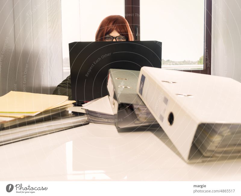 Eine Frau mit Brille sitzt am Notebook, Laptop, vor ihr sind Akten gestapelt, Arbeit bis über die Ohren! Büro Büroarbeit Business Arbeitsplatz Beruf Mensch