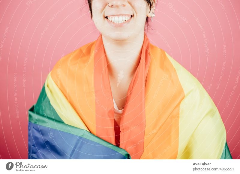 Frau, die glücklich in die Kamera lächelt, während sie eine LGBTIQ-Flagge um sich herum hält und ihren Stolz zeigt. Lesbische Frau, Stolz und Kampf für ihre Rechte. Liebe ist Liebe Konzept. Farbe Hintergrundbild