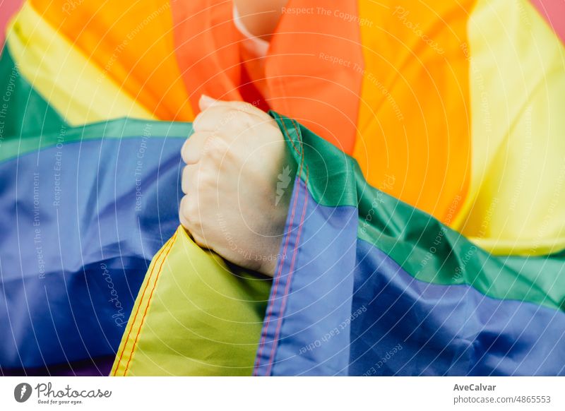 Nahaufnahme Hand über Flagge. Frau lächelt glücklich in die Kamera, während sie eine LGBTIQ-Flagge um sich herum hält und ihren Stolz zeigt. Lesbische Frau, Stolz und Kampf für ihre Rechte. Liebe ist Liebe Konzept.