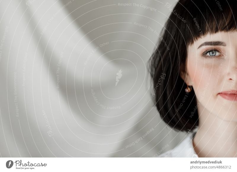 Porträt der schönen brünetten jungen Frau mit kurzen Haaren schaut in die Kamera vor dem Hintergrund einer Wand mit weißem Tuch. copy space. Leder Rock