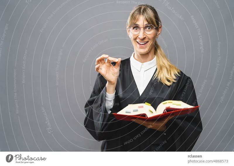 Weiblicher Rechtsanwalt mit Zivilgesetzbuch zeigt richtig Zeichen mit Hand in einem Gerichtssaal. Recht und Gerechtigkeit Konzept Bild Deutsch Anwalt Paragraph