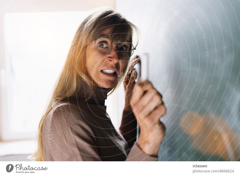 Verärgerter Lehrer mit Brille und Kreide in der Hand vor einer Wandtafel wütend kleben verrückt Groll Miesepeter Hochschullehrer Schule Tafel Person Frau