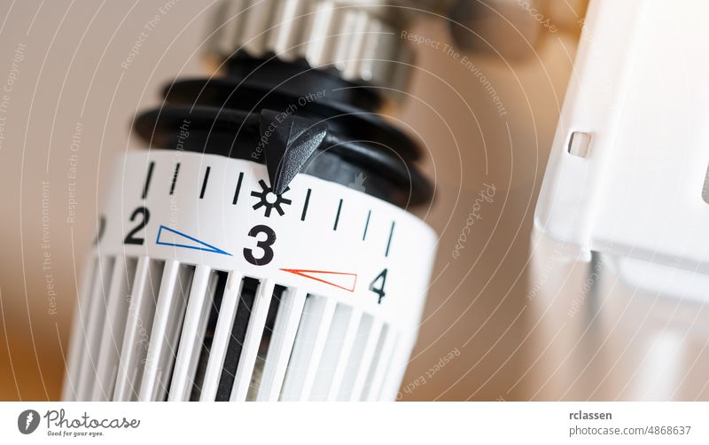 Thermostatisches Heizkörperventil auf mittlere Temperatur eingestellt, Symbol zum Sparen von Heizkosten Ventil ausrichten kalt Konsum Kontrolle Kosten Effizienz