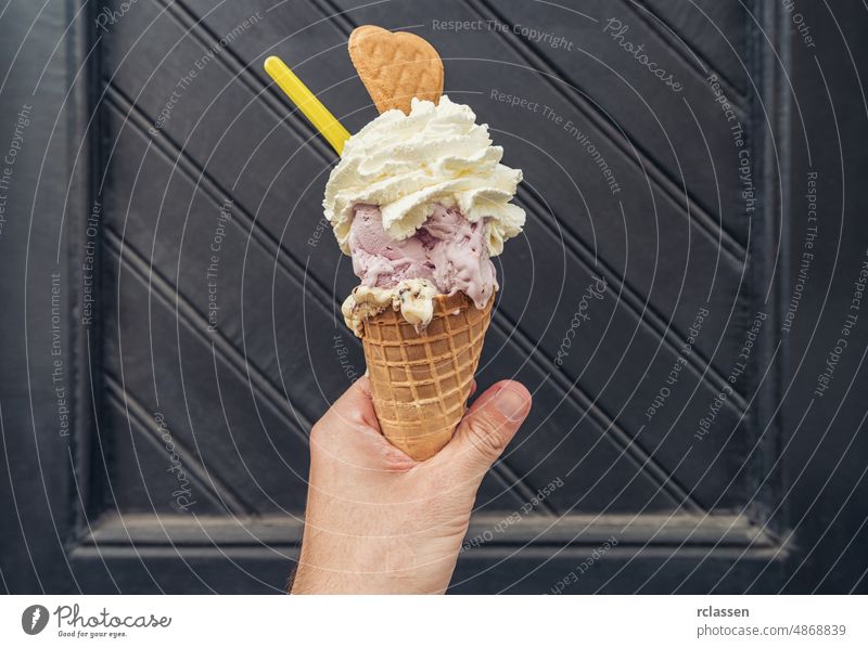 Männliche Hand hält Eis mit Sahne und Keks gegen schwarze Türschwelle. POV-Bild Beteiligung Sommer Dessert Genuss Fröhlichkeit menschliche Hand Lebensstile