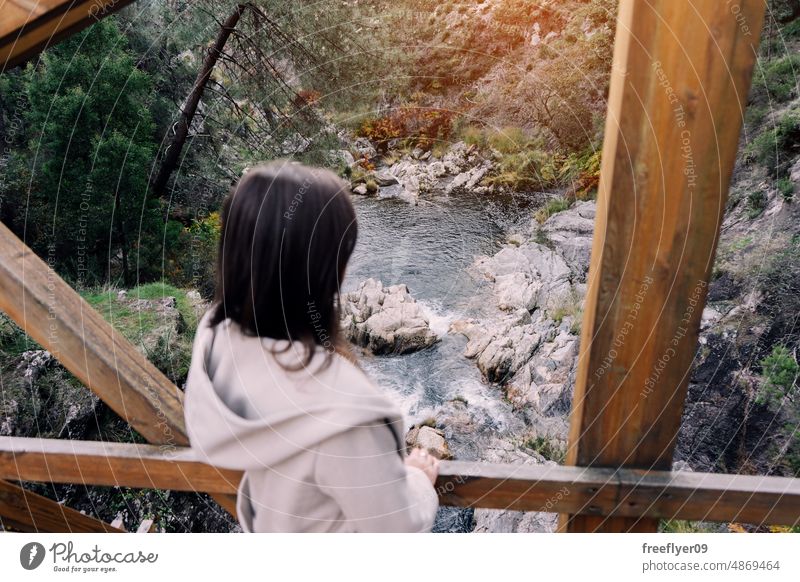 Frau, die von einer Holzbrücke aus einen Fluss betrachtet betrachtend Teich Wald Porträt jung Kaukasier Brücke Tourist laufen Berge u. Gebirge wandern