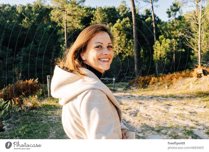 Porträt einer jungen Frau vor einem Wald Kaukasier Natur Spanisch Galicia Textfreiraum rückwärts blickend Lächeln Glück Mantel Herbst Sonnenuntergang Landschaft
