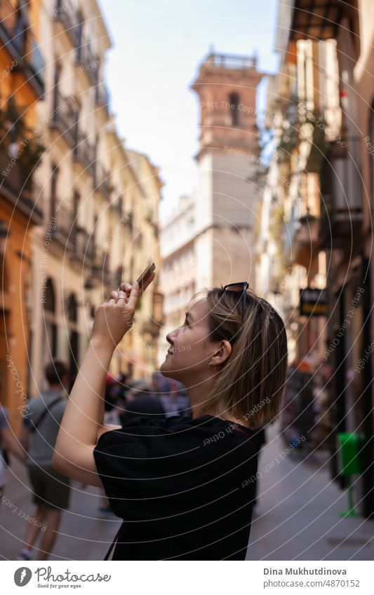 Junge Touristin fotografiert mit Handy in der Altstadt und bewundert die Aussicht auf die europäische Stadt an einem sonnigen Tag. Frau Sightseeing im Sommer im Urlaub. Hitzewelle in Europa, die Touristen und Reisende betrifft.