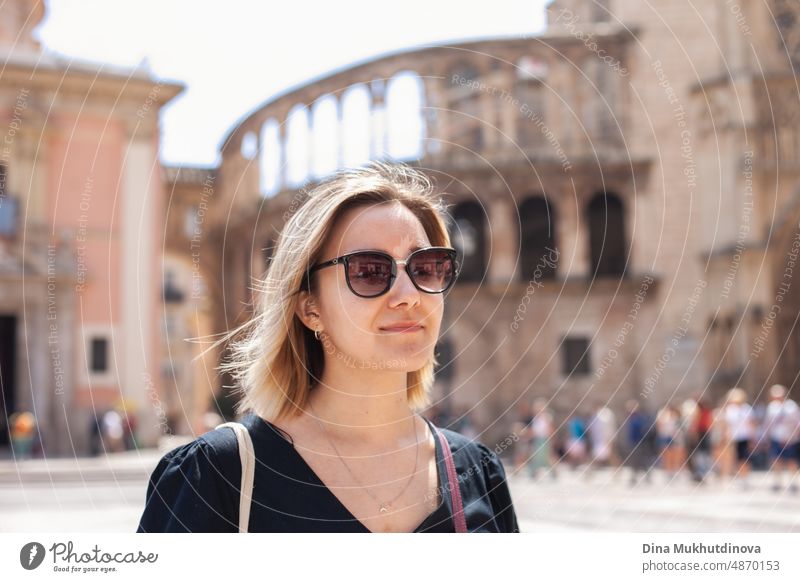 Junge Touristin mit Sonnenbrille in der Altstadt bewundert die Aussicht auf eine europäische Stadt an einem sonnigen Tag. Frau beim Sightseeing im Sommer im Urlaub. Hitzewelle in Europa, die Touristen und Reisende betrifft.