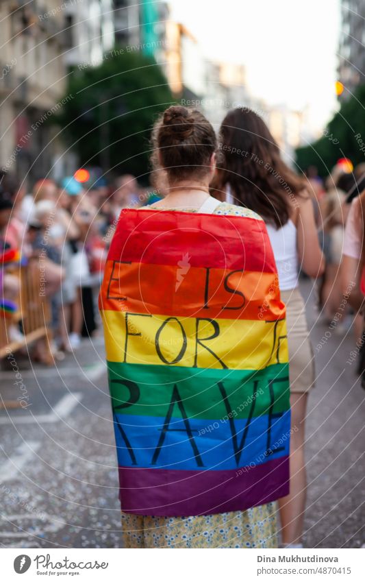 Frau von hinten mit Regenbogenfahne mit der Aufschrift "Pride": Liebe ist nur für die Tapferen. LGBTQIA+ Unterstützung und Verbündete. Pride-Parade in den Straßen einer europäischen Stadt.