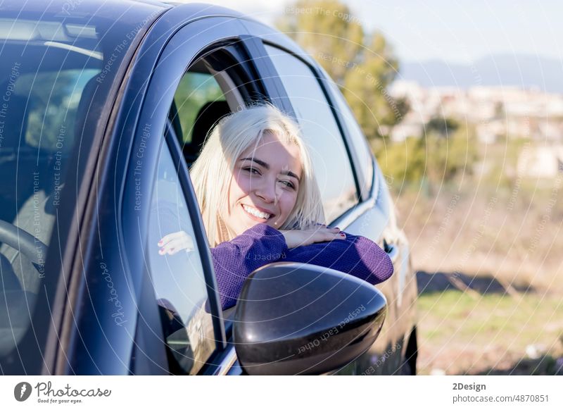 Lächelnde junge Frau schaut aus einem Autofenster PKW Reise Fenster die Arme verschränkt Person Urlaub reisen Lehnen Erwachsener Glück Verkehr Porträt im Freien