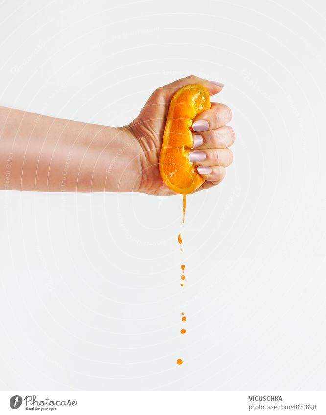 Frau drückt mit der Hand Orangenhälften vor weißem Hintergrund aus, der Saft tropft. quetschend Hälften orange weißer Hintergrund tropfend Vorderansicht