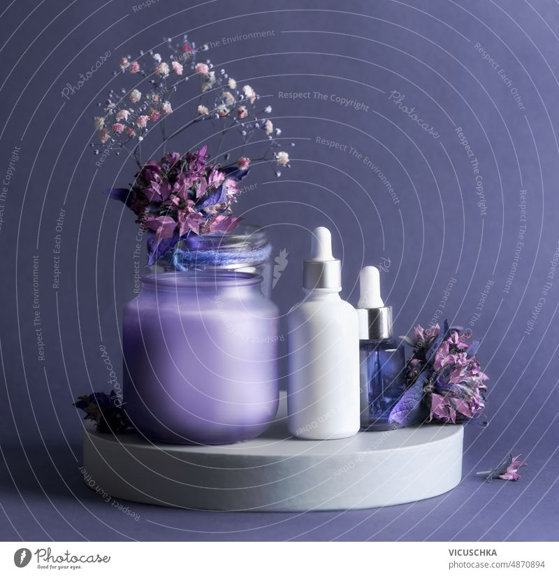 Lila Beauty-Produkt-Set mit Kosmetikserum-Flaschen, Kerze und Blumen. purpur Schönheitsprodukt Einstellung Serum Gesundheit Hautpflege Produkte