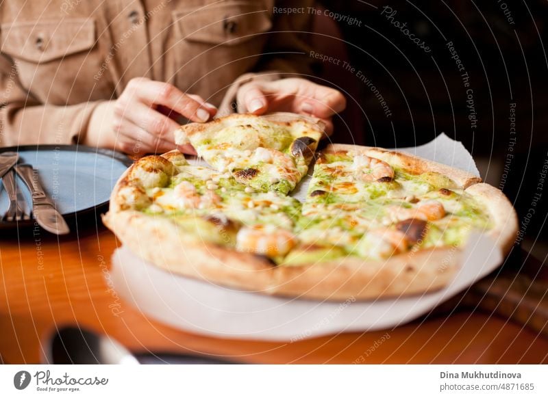 Pizza essen in einer Pizzeria. Pizza Nahaufnahme im Karton - Pizzalieferung und Essen zu Hause. Fast Food Gewohnheiten. Pizzabestellung per App und Lieferung nach Hause. Frau isst Pizza im Restaurant, nimmt ein Stück.