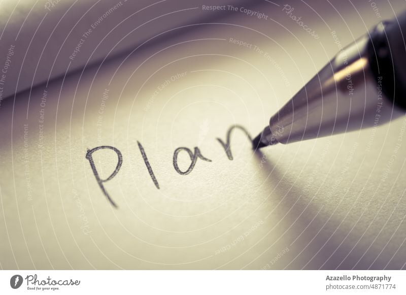 Nahaufnahme des Schreibens eines Wortes PLAN auf einem Notizbuchpapier. Aufgaben Plan Hinweis abschließen Makro Schreibstift schreibend Minimalismus Idee