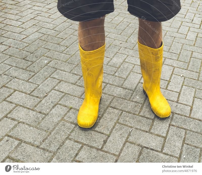 Männerbeine in gelben Gummistiefeln. Der Regen kann kommen... Beine in Gummistiefeln Pflastersteine Stiefel Schuhe Mensch Mann kurze Hose stehen Straße Wetter 1