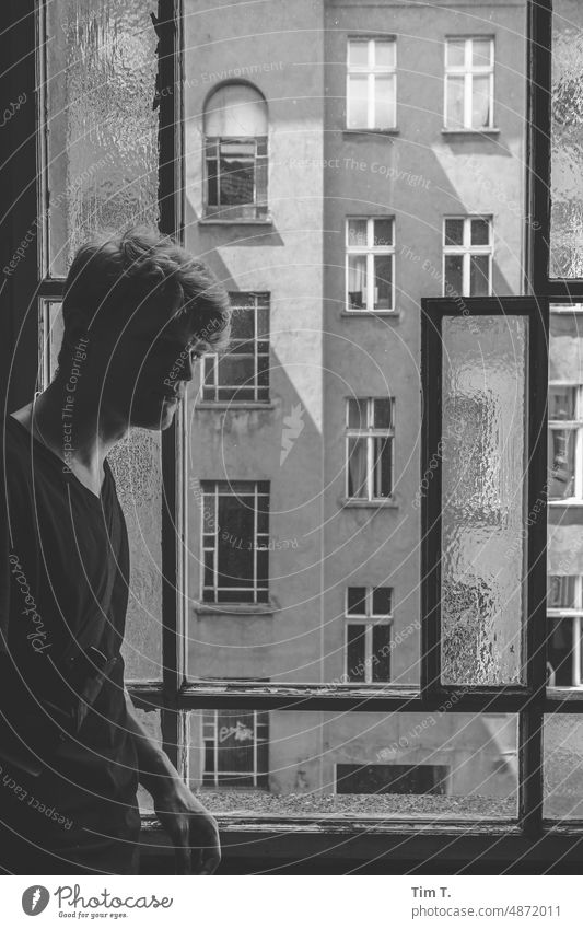 ein junger Mann am Treppenhausfenster Altbau unsaniert bnw Schwarzweißfoto Prenzlauer Berg Fenster Innenhof s/w blond Stadt Stadtzentrum Tag Hauptstadt Berlin