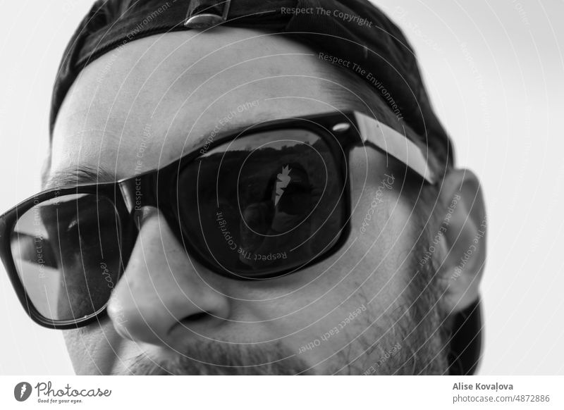 Fotograf in einer Spiegelung Sonnenbrille Reflext Gesicht männlich Mann Porträt Rückwärtshut Vollbart schwarz auf weiß siehe Trog dunkel dunkle Brille