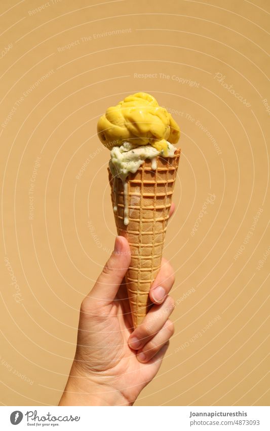 Gelbes Waffel Eis in Hand vor gelber Wand Fruchteis Speiseeis Sommer süß Dessert Lebensmittel Erfrischung lecker