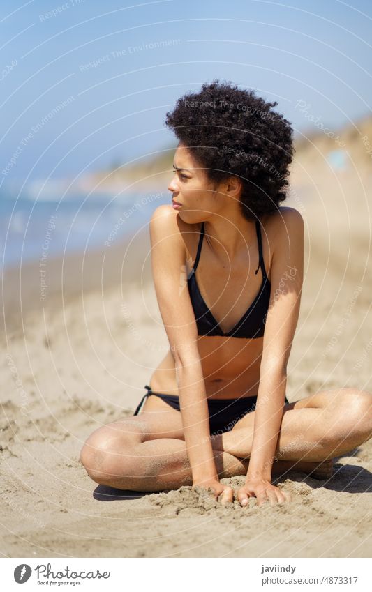 Schwarze Frau im Bikini sitzt am Meer Strand MEER Ufer Sommer Badebekleidung Meeresküste Kälte sonnig Freizeit Erholung Ausflug Meeresufer Sand schwarz ethnisch