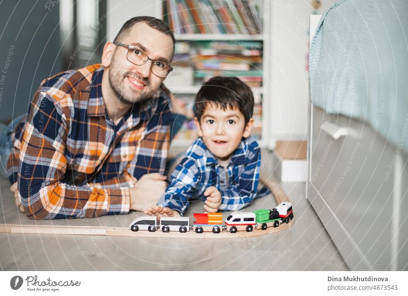 Vater und Sohn spielen mit Spielzeug-Eisenbahn und Zug. glückliche Familie verbringt Zeit zusammen. Vater und Sohn. Elternschaft und Vatertag. Kindheit Design